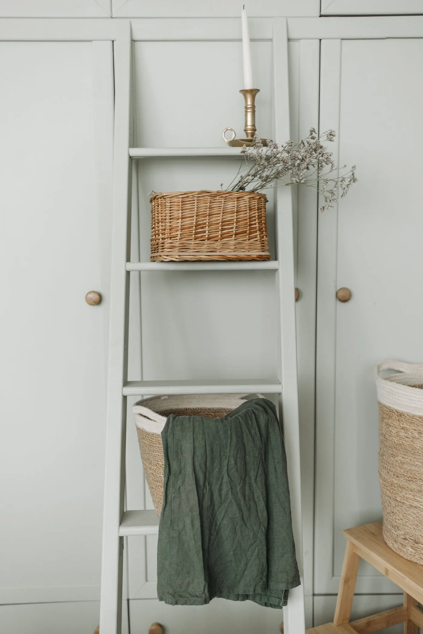Elegant interior with wicker baskets, a ladder, and candle for a vintage look.